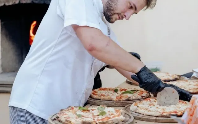 Un bambino tira la sfoglia accanto a un adulto su un tavolo di cucina a Firenze