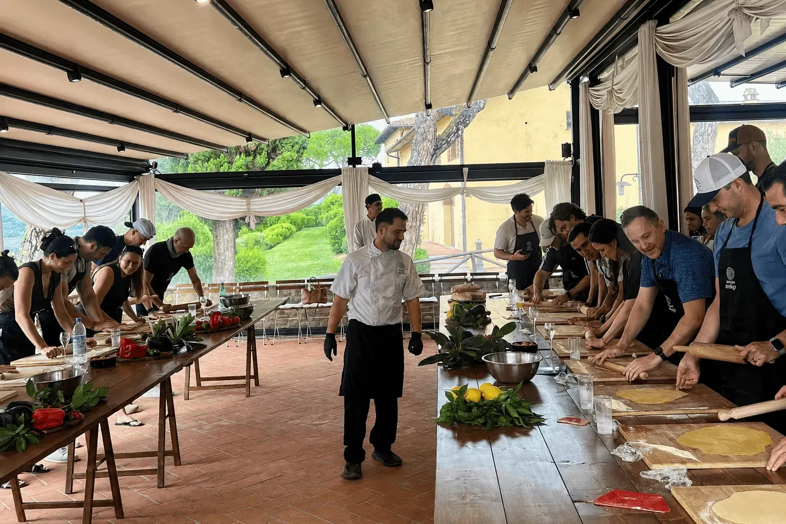 A corporate team cooking fresh pasta together at a long table in a private Florence kitchen