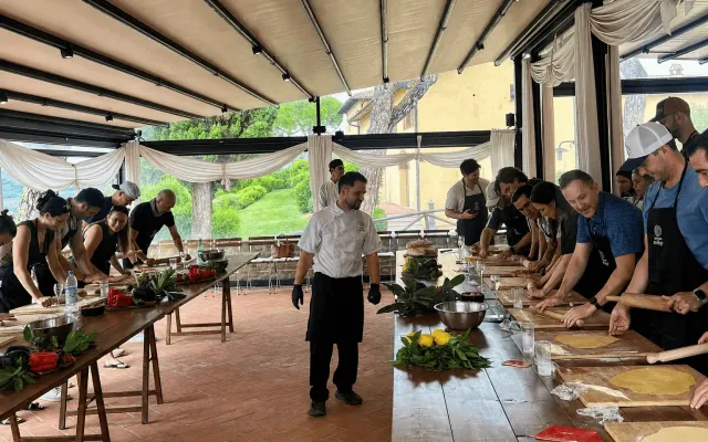 A corporate team cooking fresh pasta together at a long table in a private Florence kitchen