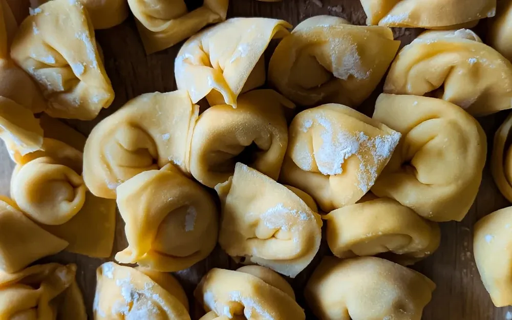 Plump potato-filled tortelli pasta parcels, sealed by hand and laid out in rows